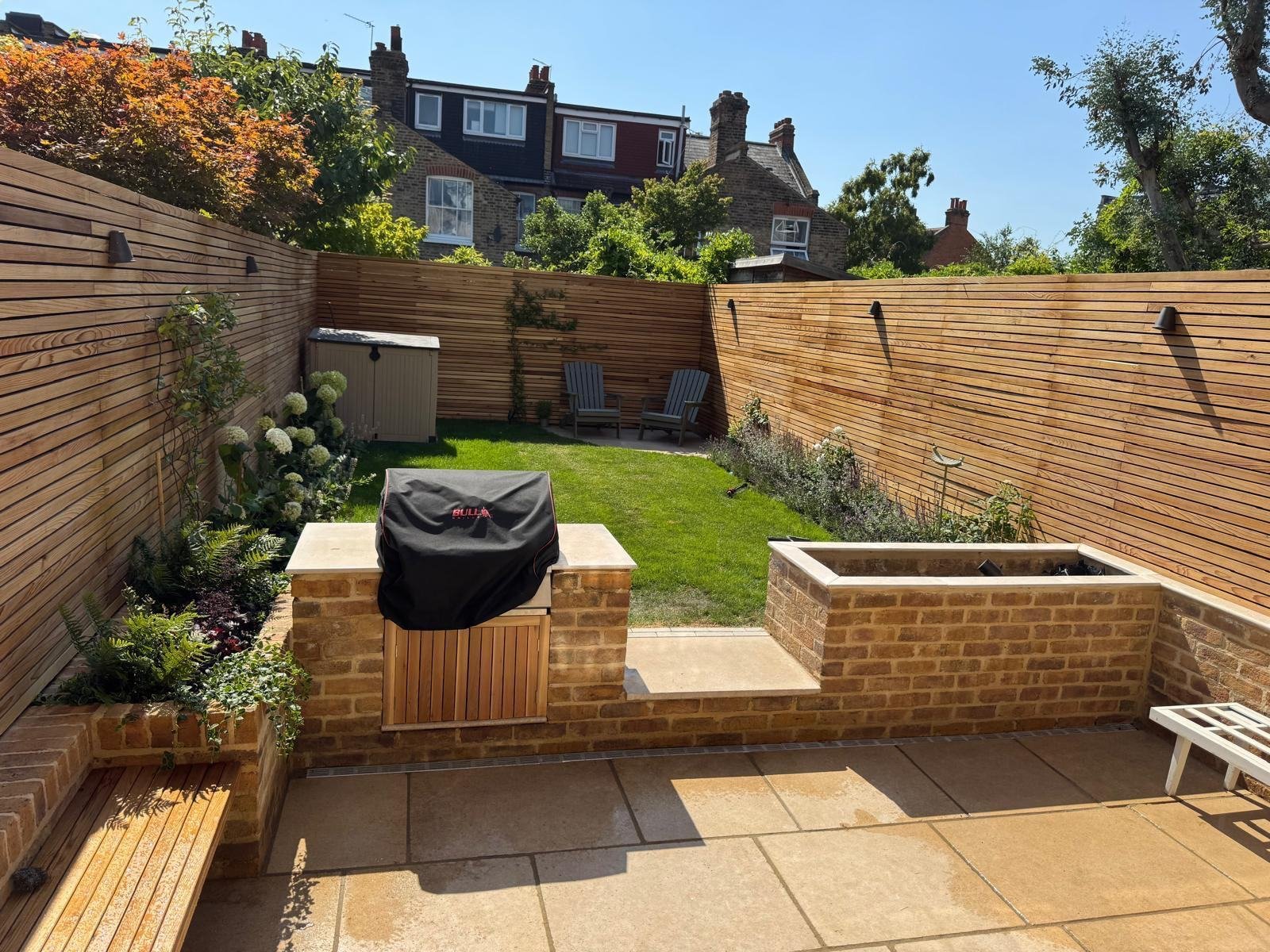 The same garden finished, paved patio, brick barbecue surround, raised beds, slatted fence and lawn