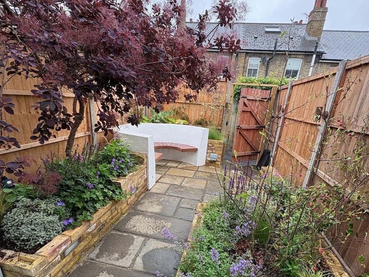 The same garden finished, white rendered curved bench with a timber seat, brick raised beds, riven stone paving and new close-board fencing