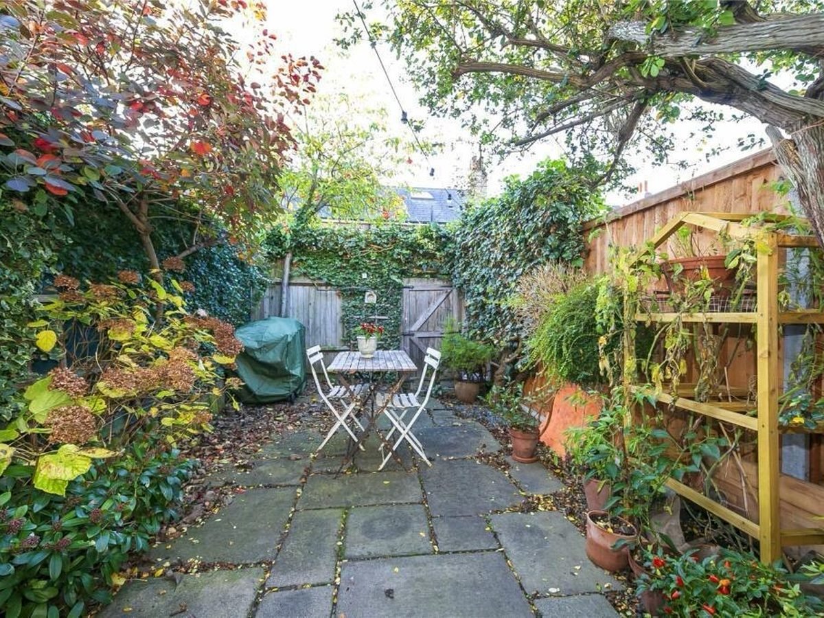 Long narrow garden before work, cracked flagstone paving, overgrown borders and an ivy-covered wall