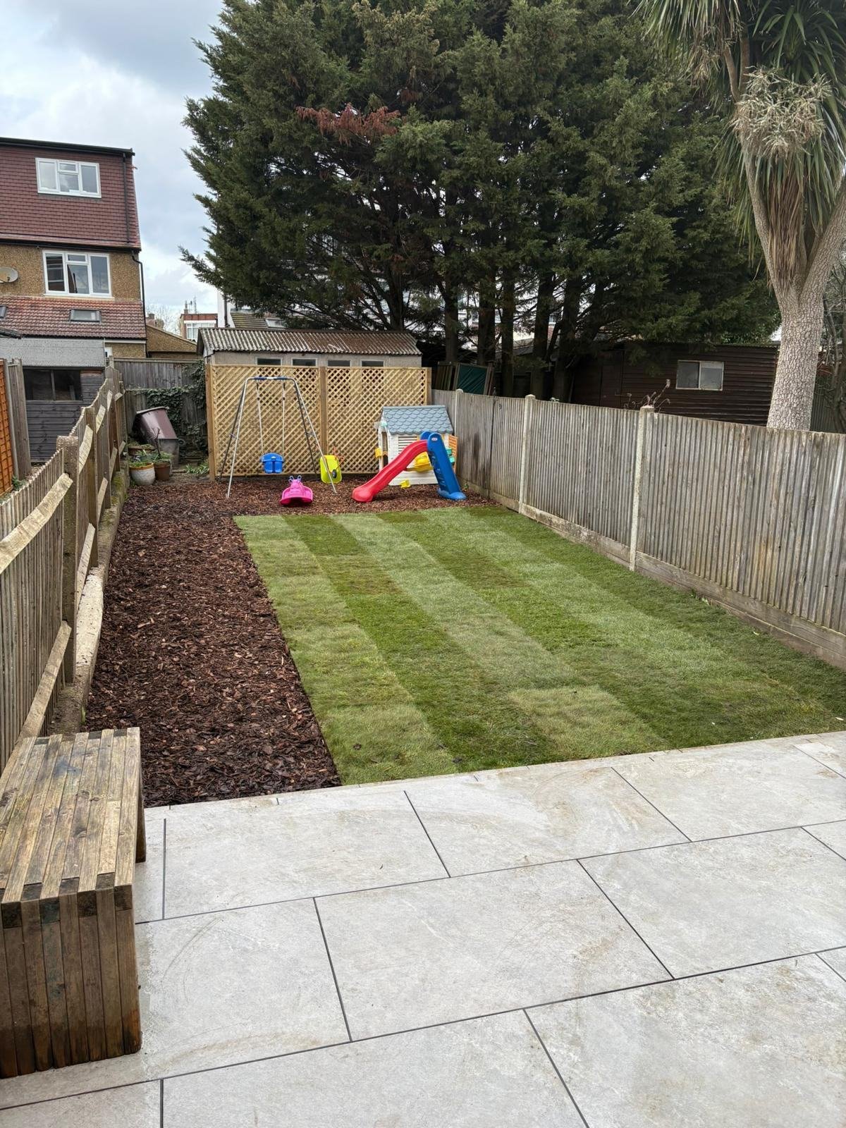 The same garden finished, striped new lawn, bark border, patio and children's play equipment